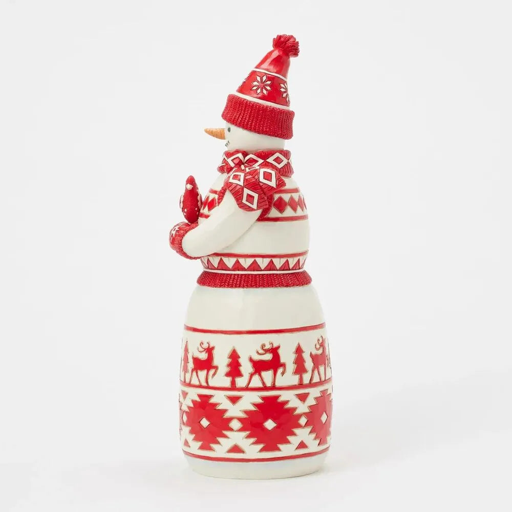 Side view of Nordic snowman figurine holding a red bird, Fair Isle skirt with reindeer and geometric bands, red pom-pom hat