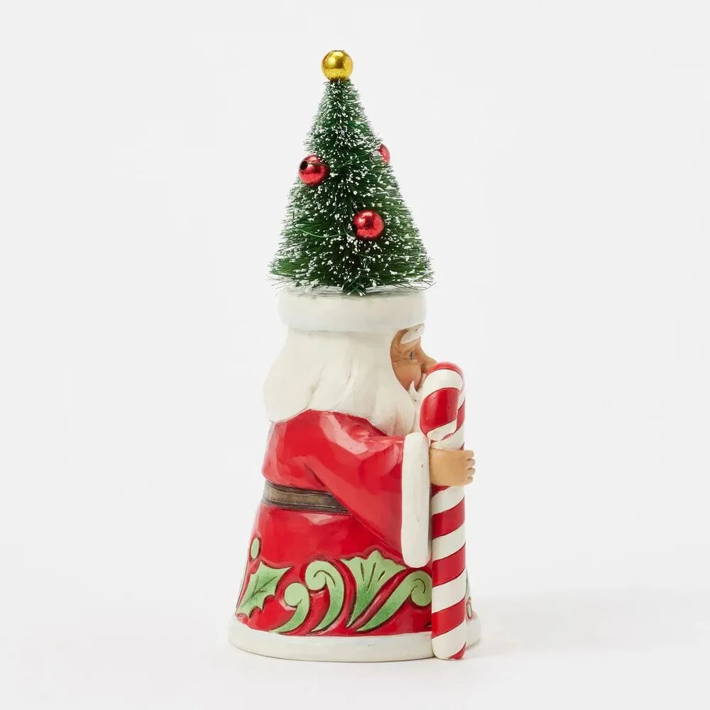 Side view of Santa gnome figurine with bottle brush Christmas tree hat, holding a candy cane, red robe with green scrollwork hem