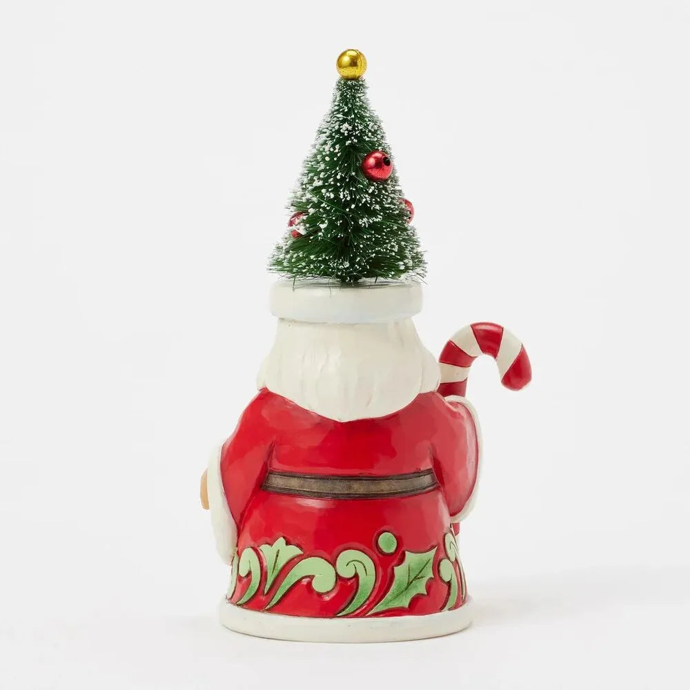 Rear view of Santa gnome figurine showing bottle brush tree hat with red ornaments, holly scrollwork robe hem, candy cane visible at side