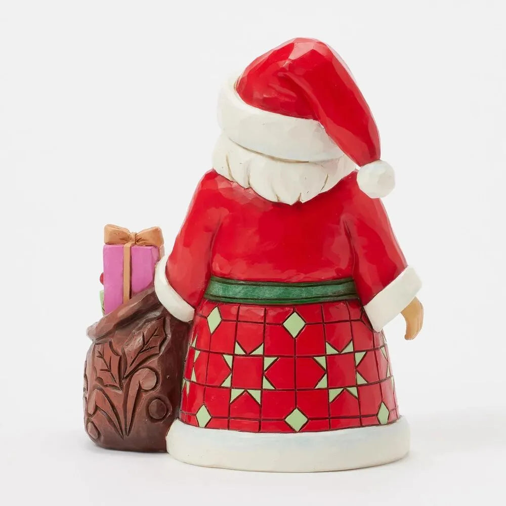 Rear view of Santa figurine showing red and green diamond-patterned robe, green sash, and scrollwork gift sack with wrapped presents