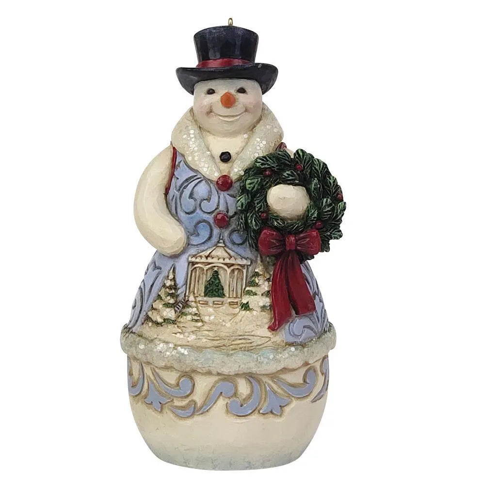 Front view of a Jim Shore snowman hanging ornament holding a wreath with red bow, winter scene on coat, black top hat