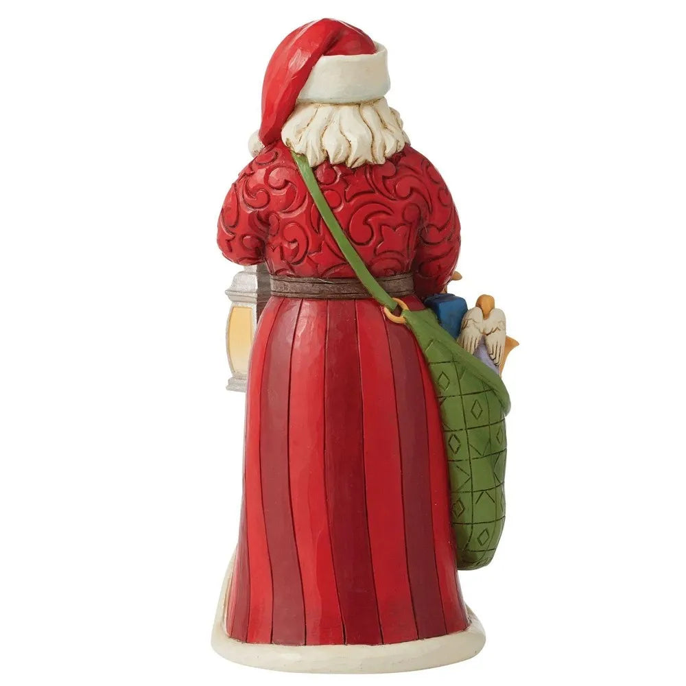 Rear view of Santa figurine in red scrollwork coat carrying a green toy-filled sack and lantern, stripe-detailed robe