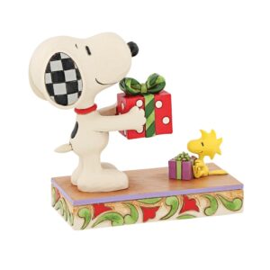 Jim Shore Snoopy figurine holding a wrapped Christmas gift beside Woodstock on a decorative base
