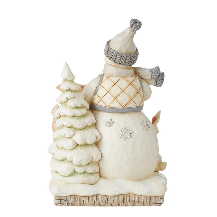 Rear view of Jim Shore white woodland snowman figurine wearing knitted hat beside a snowy tree
