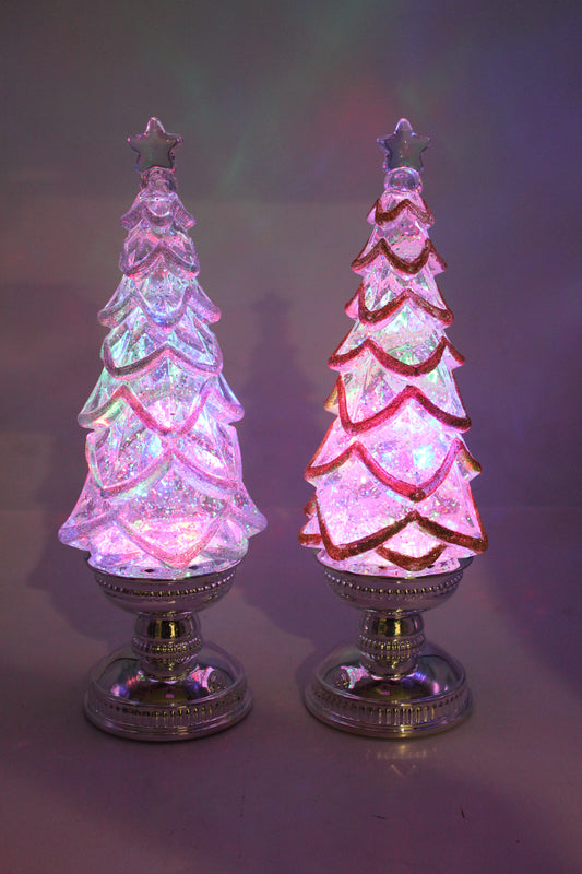 Two decorative glass Christmas trees with colorful lights on a reflective surface.