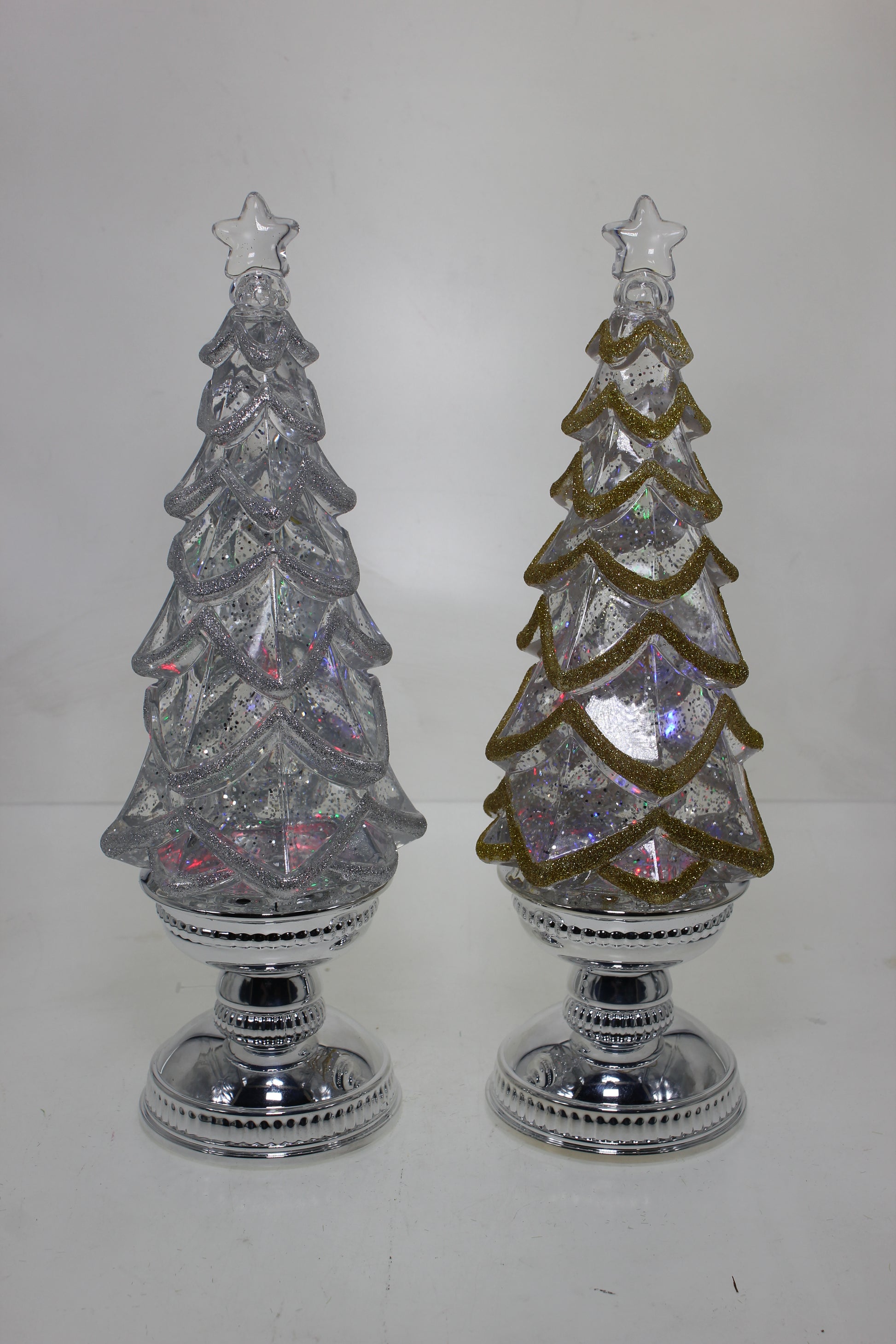 Two decorative Christmas trees with crystal-like finishes on a white background