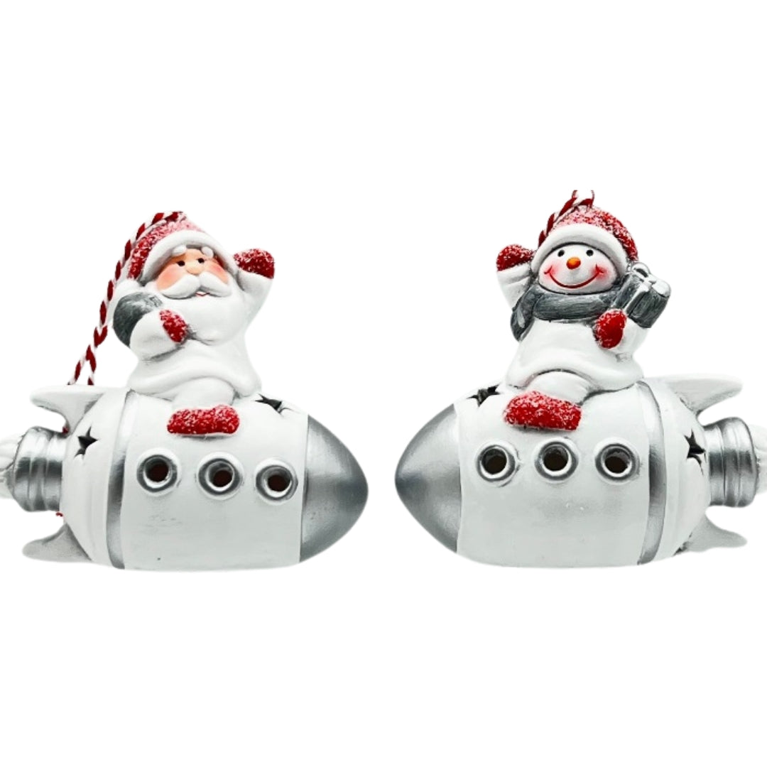 Two white and silver rocket decorations, one with Santa and one with a snowman, with porthole windows