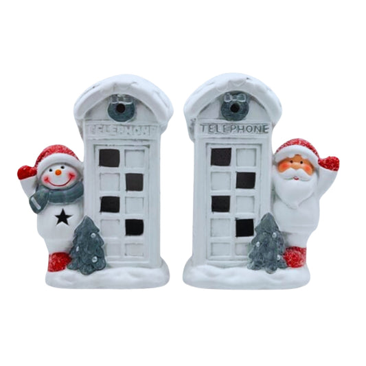 Two light-up snowy white telephone box decorations, one with a snowman and one with Santa, beside small trees