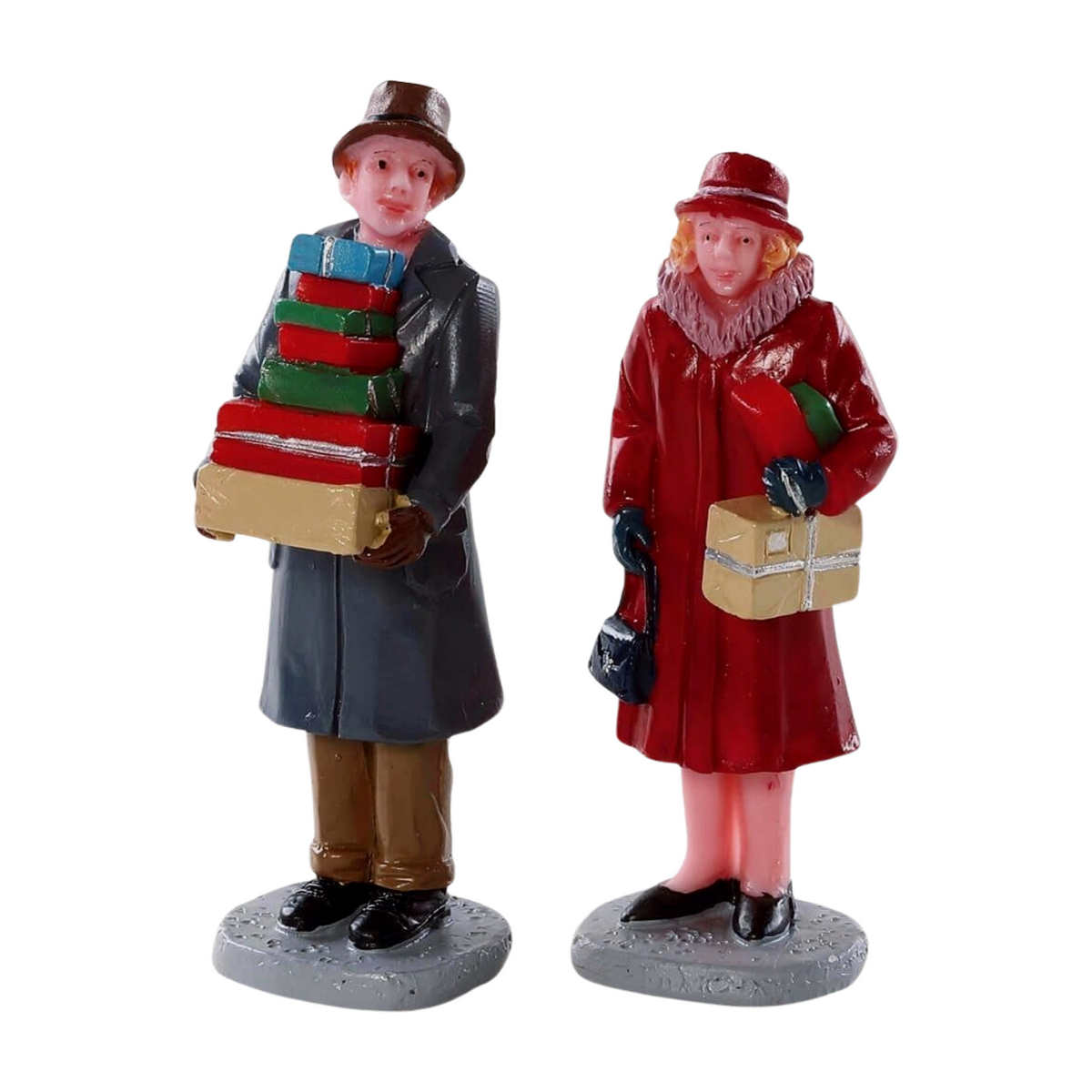 Two Lemax Christmas shopper figurines — a man carrying a stack of gifts and a woman in a red coat holding parcels