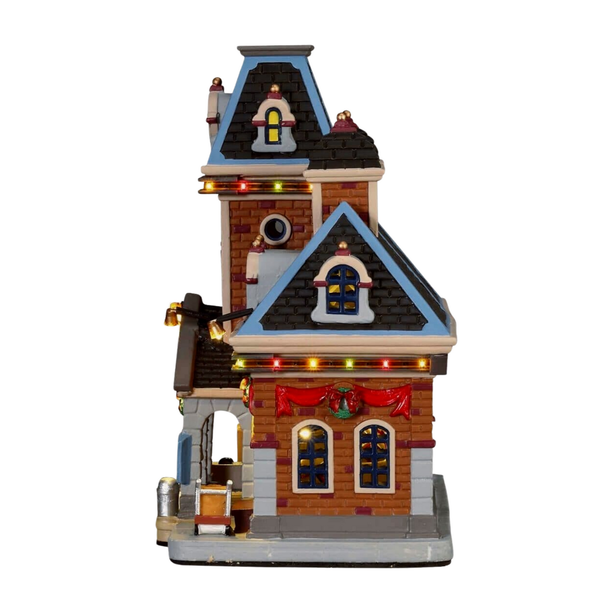 Left view of Lemax Christmas village train station wing with dark roofline, multicoloured lights, arched windows, and wreath