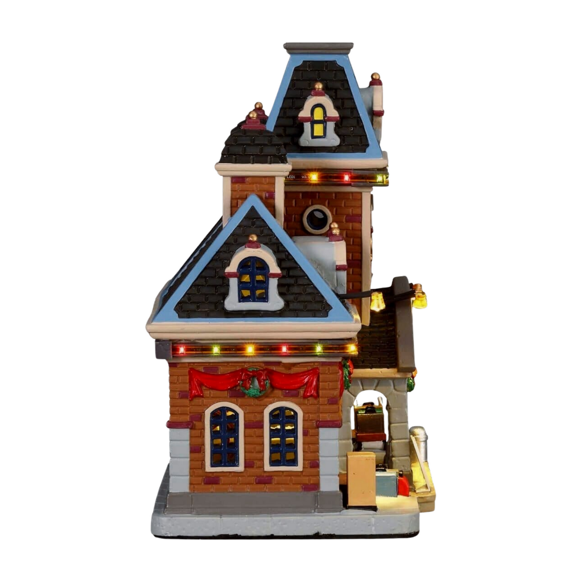 Right view of Lemax Christmas village train station building with dark tiled roof, red and amber lights, and luggage platform