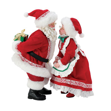 Santa and Mrs Claus figurine set standing face to face, Santa holding a wrapped Christmas gift
