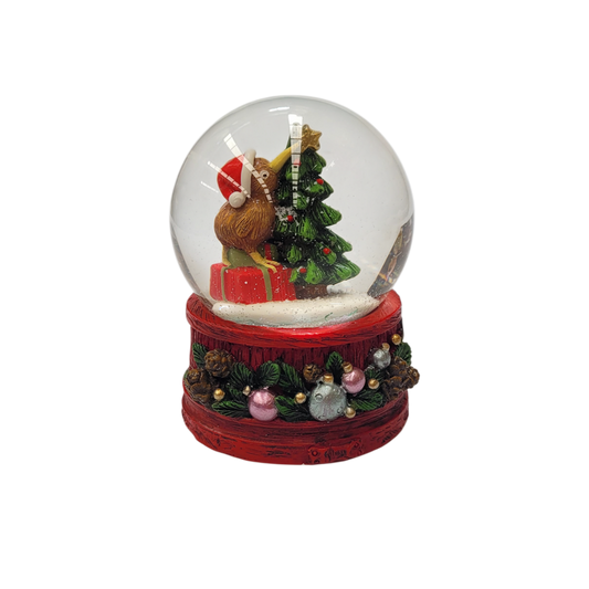 Snow globe with a kiwi bird in a Santa hat beside a Christmas tree on a red decorative base