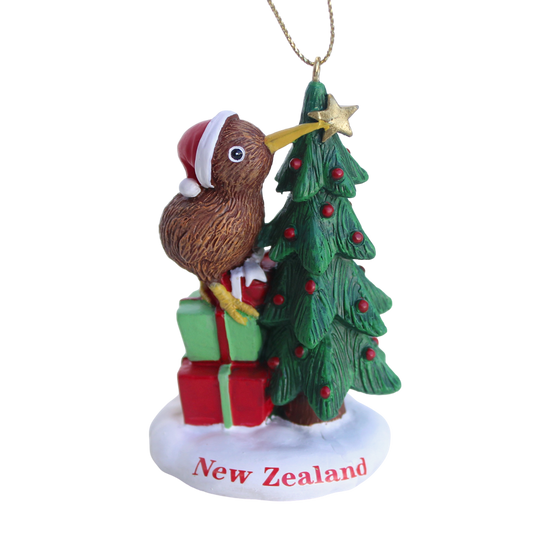 NZ kiwi bird in a Santa hat placing a star on a Christmas tree with gifts hanging ornament