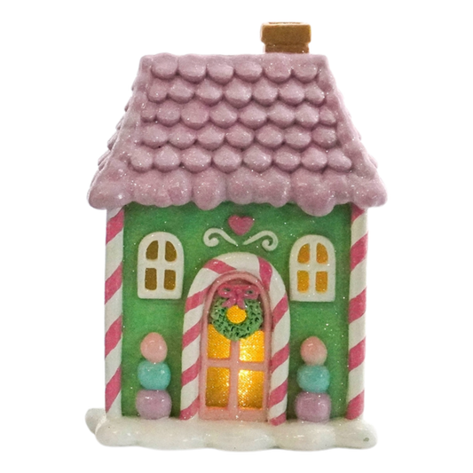 Pastel green candy house with a lilac-pink roof, candy cane arch and glowing amber windows