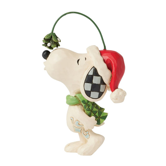 Snoopy figurine in Santa hat and green scarf, nose raised toward mistletoe on a wire, checkered ear detail