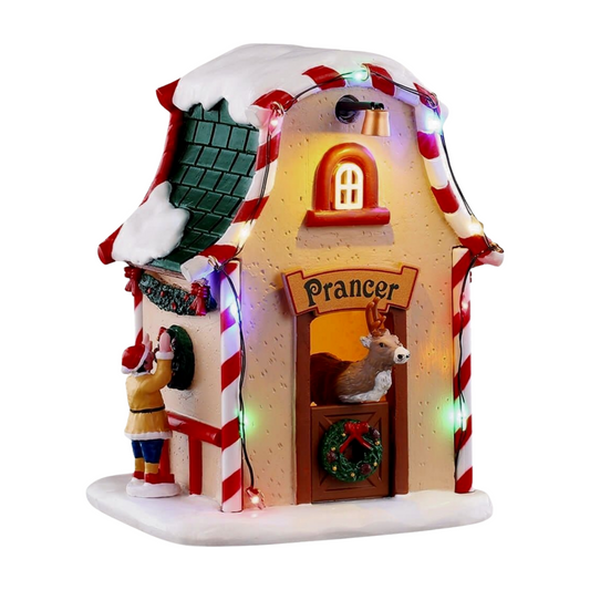 Front of Prancer's reindeer stable village building with candy cane columns, Prancer sign, reindeer in doorway, and elf figurine