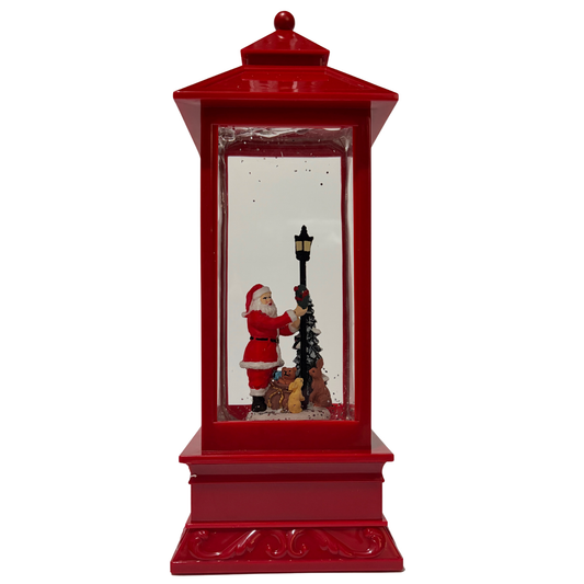 Red Christmas lantern snow globe featuring Santa beside a lamppost with swirling glitter.