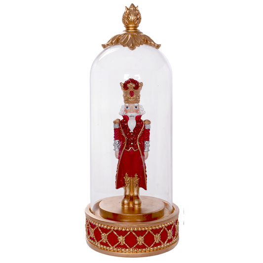 Red and gold nutcracker figurine in sequin coat and jewelled crown, housed in a glass dome on a decorative base