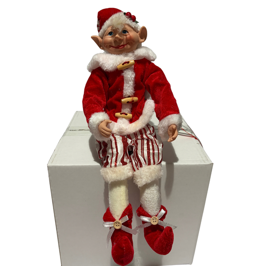 Sitting Christmas elf in red velvet jacket with white fur trim and striped trousers