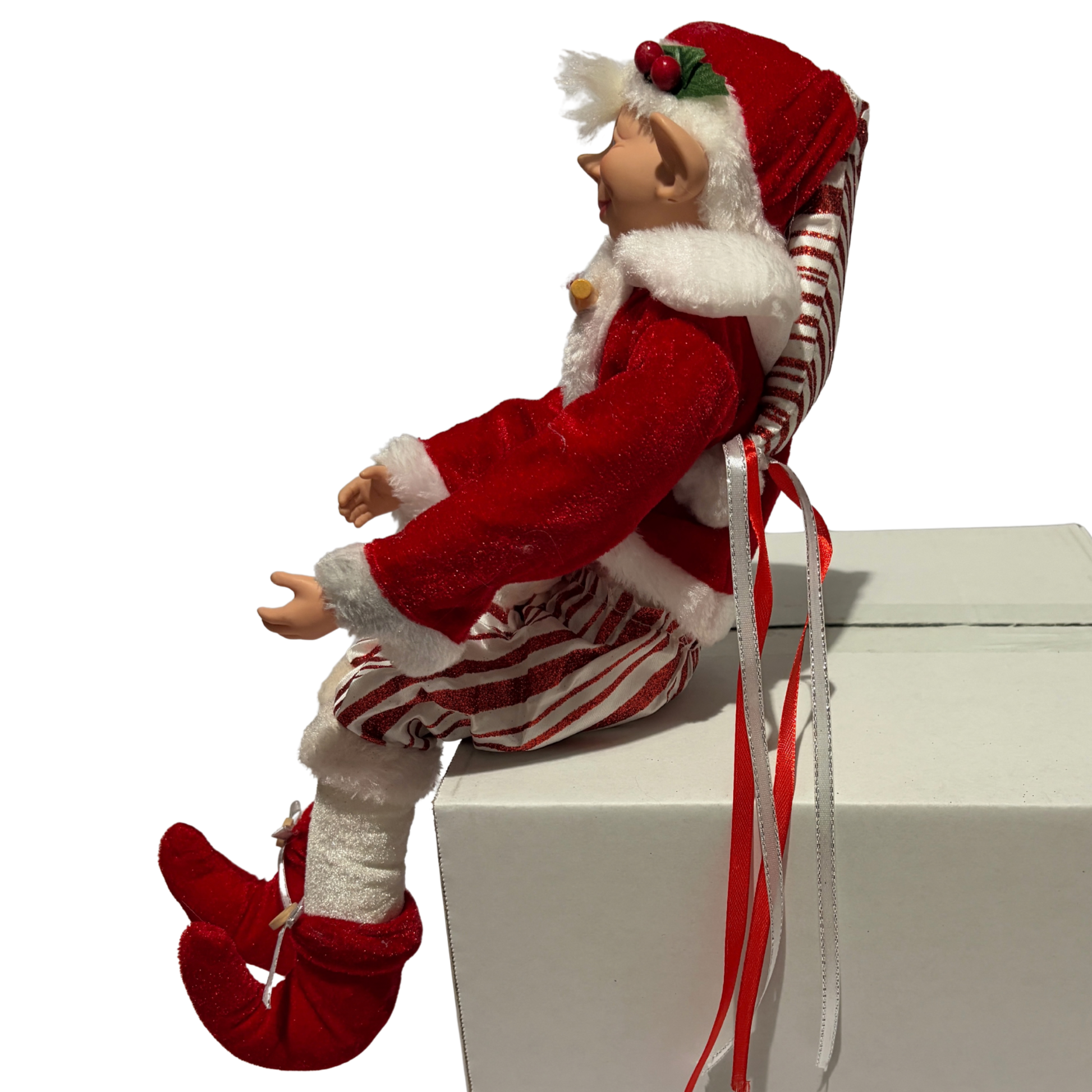 Elf figurine in red and white outfit with candy cane hat on a white box
