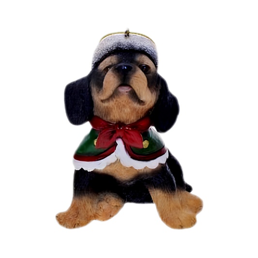 Sitting rottweiler puppy ornament wearing a green fur-trimmed cape with red bow and winter hat