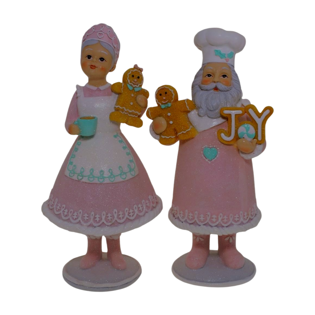 Two pastel Santa and Mrs Claus figurines holding gingerbread cookies and a “JOY” sign