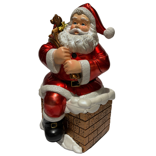 Santa ornament sitting on a snow-covered chimney holding a sack of toys