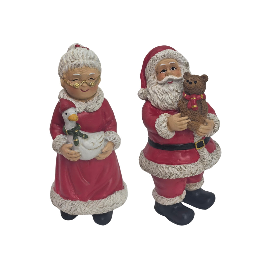 Mrs Claus holding a goose and Santa holding a teddy bear, both in red with white fur trim