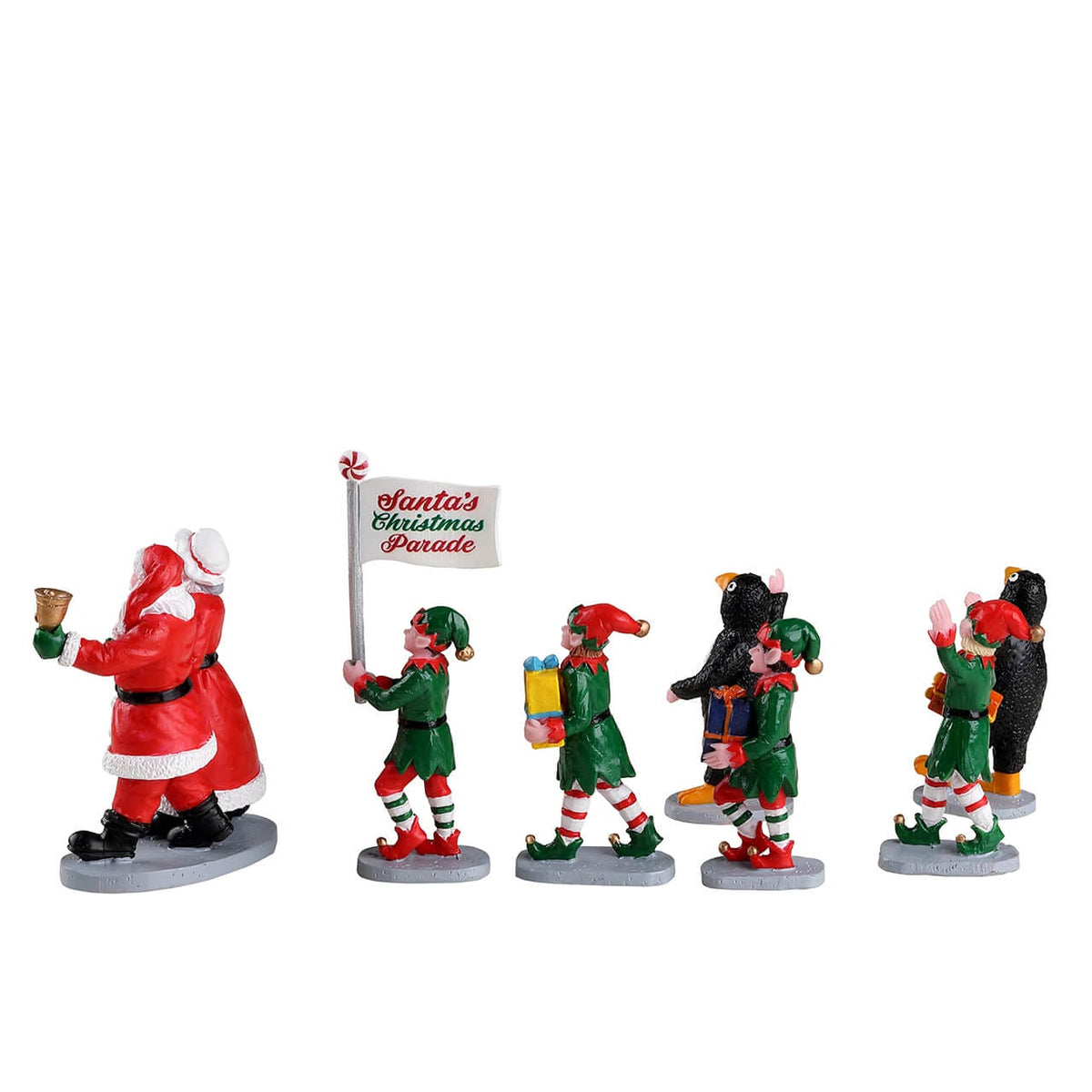 Lemax parade figures showing penguin-costumed children, gift-carrying elves, Santa and Mrs Claus