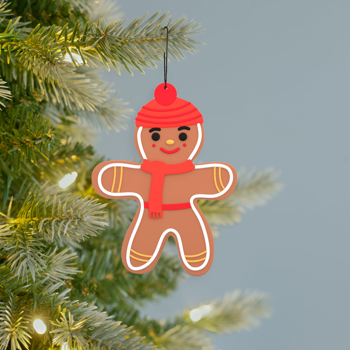 Scentsicles gingerbread man ornament hanging on a lit Christmas tree branch