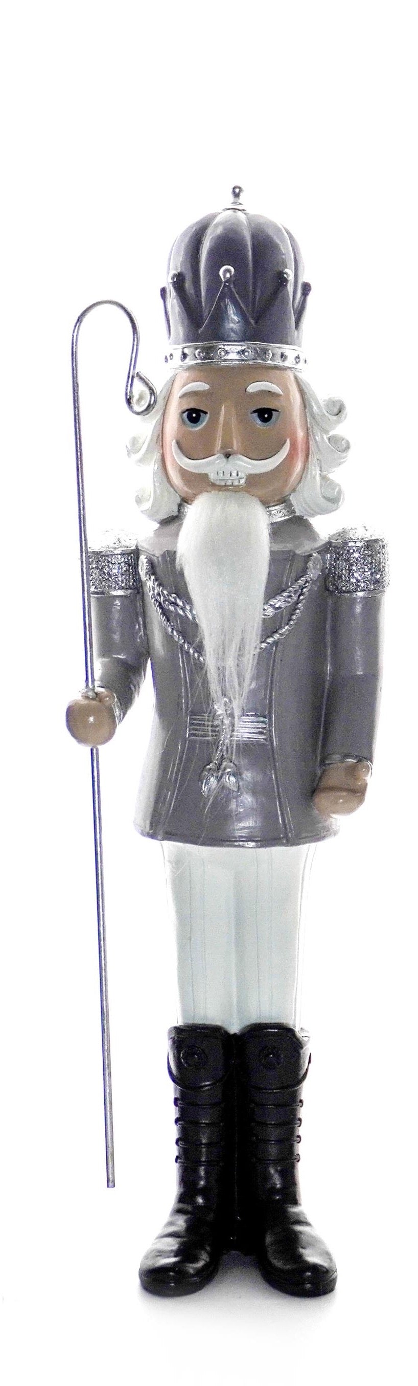 Silver nutcracker soldier holding a trumpet, wearing silver jacket and tall black boots