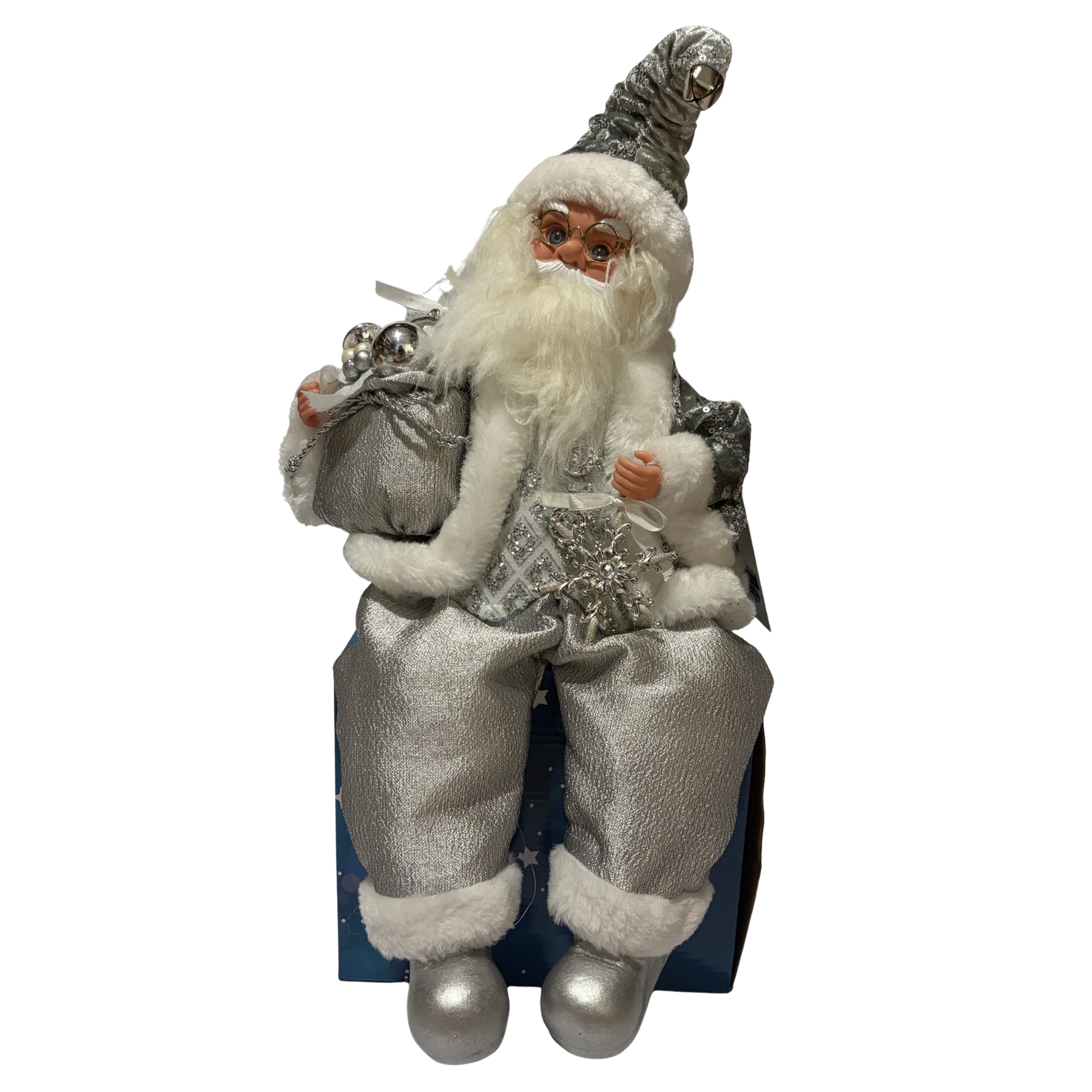 Sitting Santa Claus wearing silver with sequin accents, holding a sack of presents in one hand and a snowflake decoration in the other
