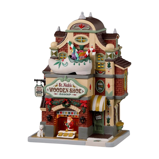 Front view of St. Nick's Wooden Shoe Shop village building with oversized shoe, Santa, holiday wreaths, and striped awning