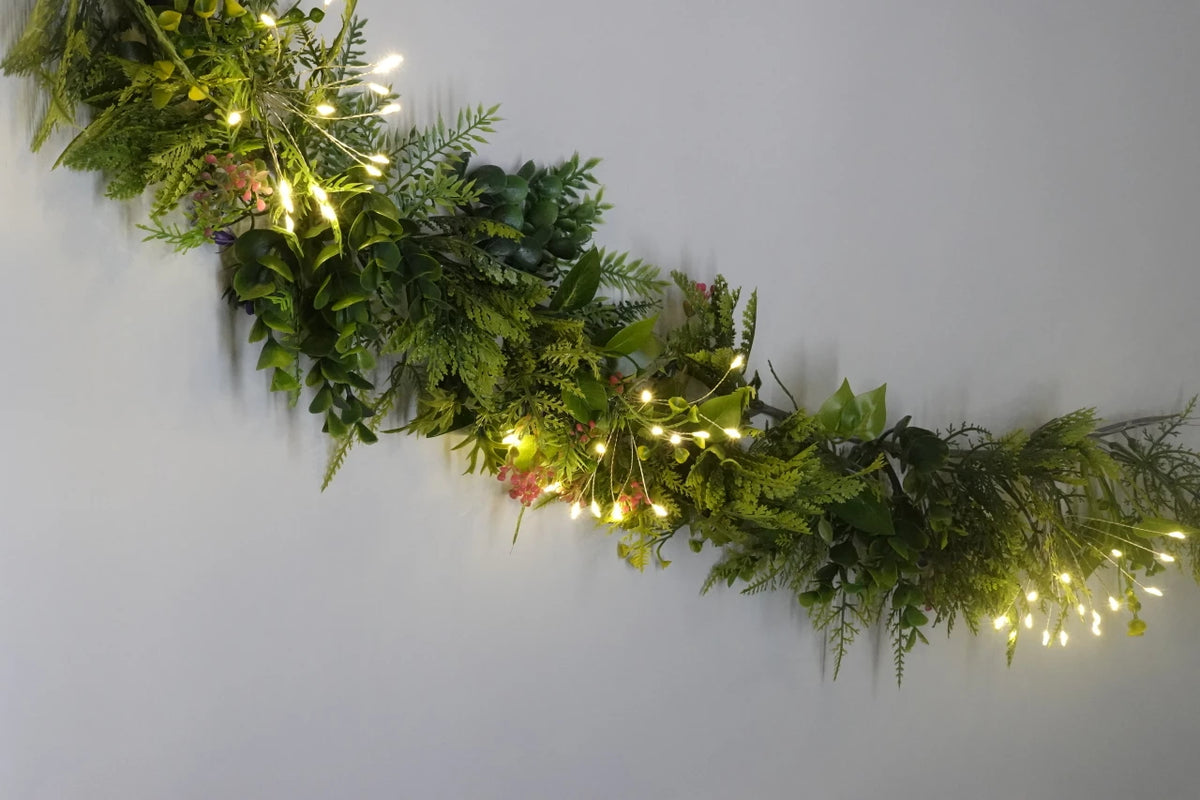 Starburst LED fairy lights woven through a green garland draped along a staircase