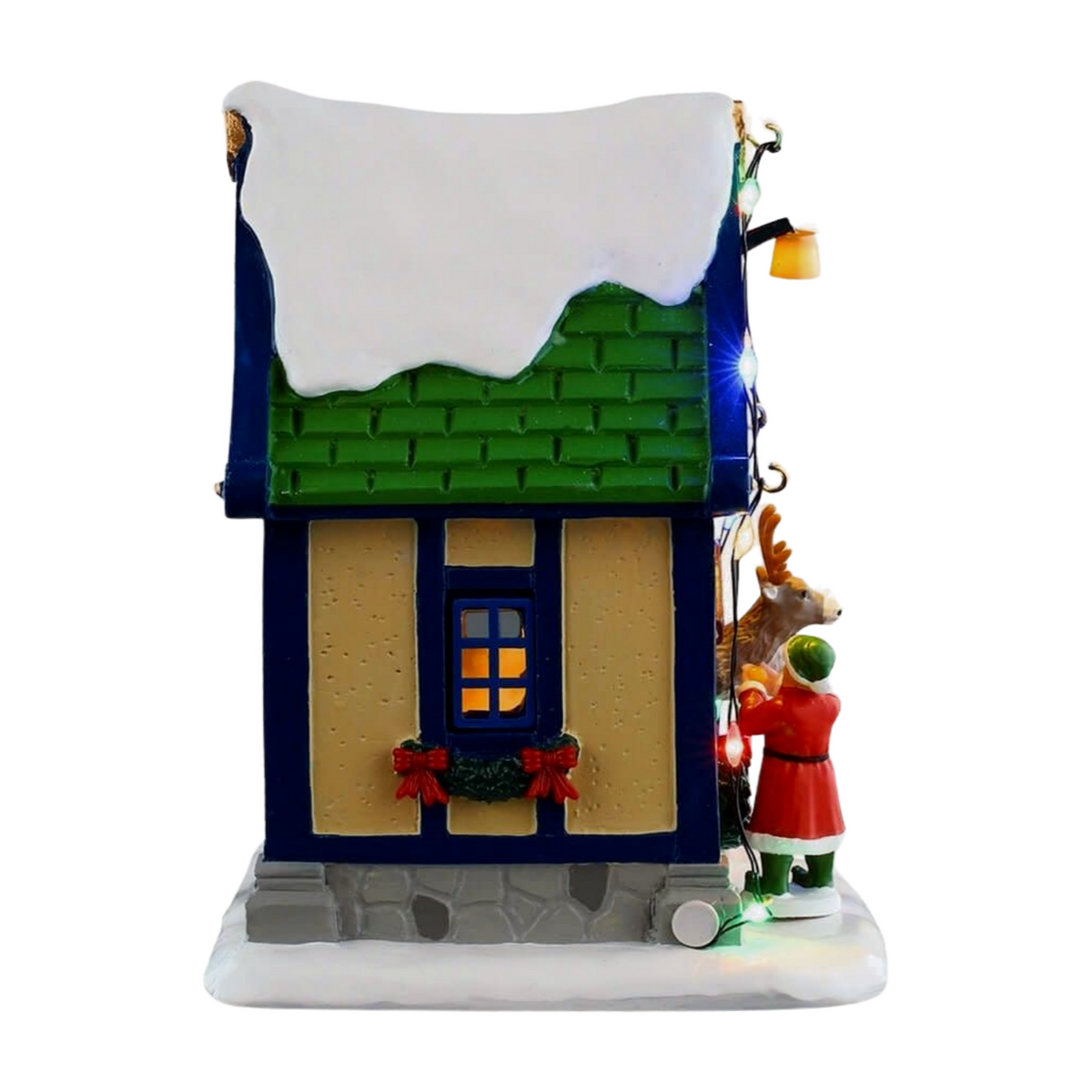 Right view of Vixen's reindeer stable village building with blue trim, lit window, red bow window box, and elf and reindeer figurines