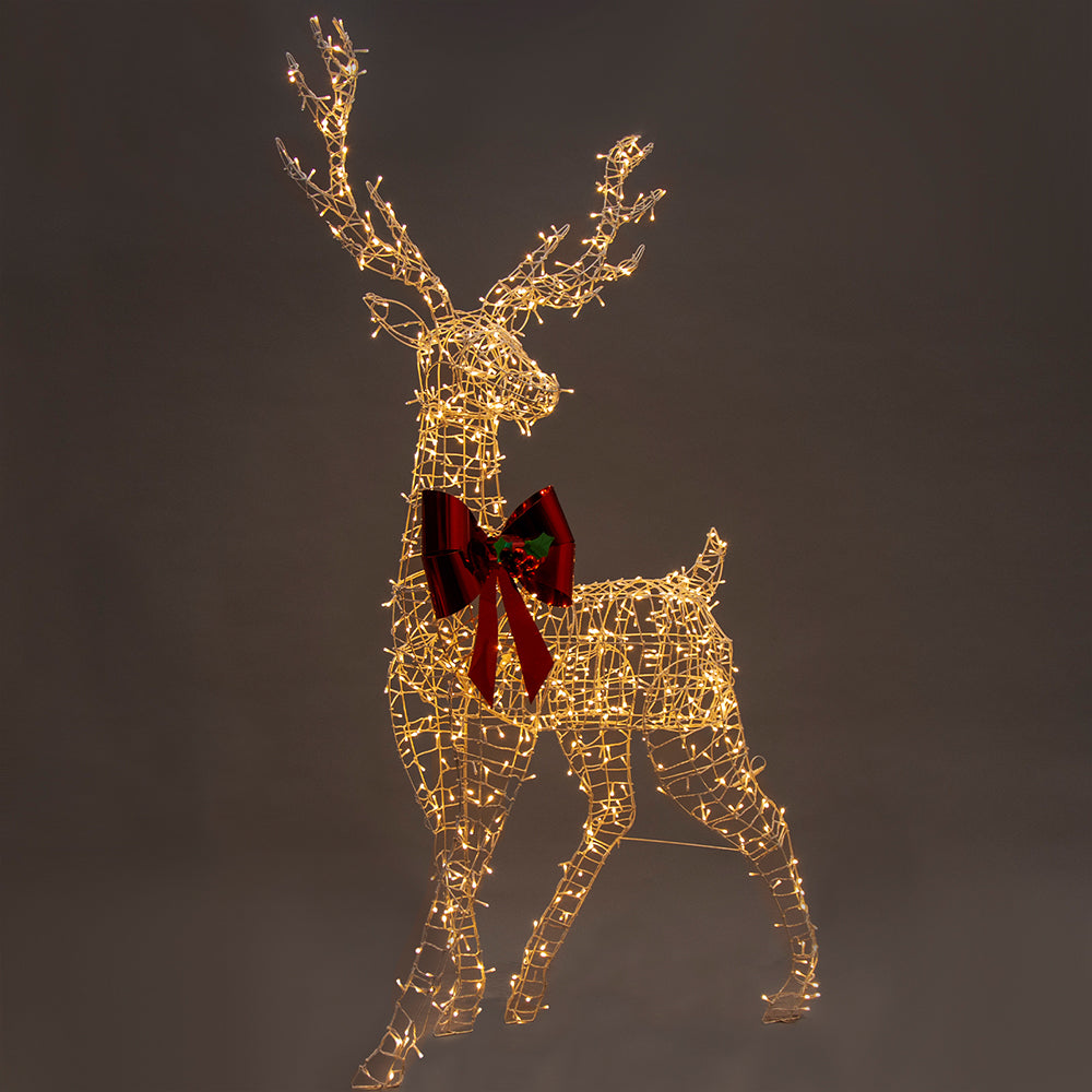 Gold wire reindeer LED light figure with red bow, side view lit with warm white lights
